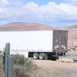 Semi-truck and damaged vehicles at accident scene in desert landscape with hills