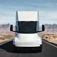 White Tesla Semi driving on desert highway with mountains in background