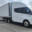 White Tesla Semi electric truck with refrigerated trailer parked in industrial lot