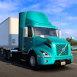 Turquoise Volvo semi-truck with white refrigerated trailer parked on highway