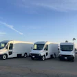 Three white Workhorse W56 commercial delivery vans parked in a row on an asphalt lot with palm trees visible in the background