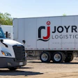 White commercial truck and Joyride Logistics LLC branded trailer parked at logistics facility