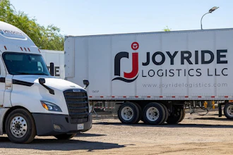White commercial truck and Joyride Logistics LLC branded trailer parked at logistics facility