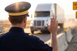 Officer in uniform stopping truck at checkpoint with warning signs visible