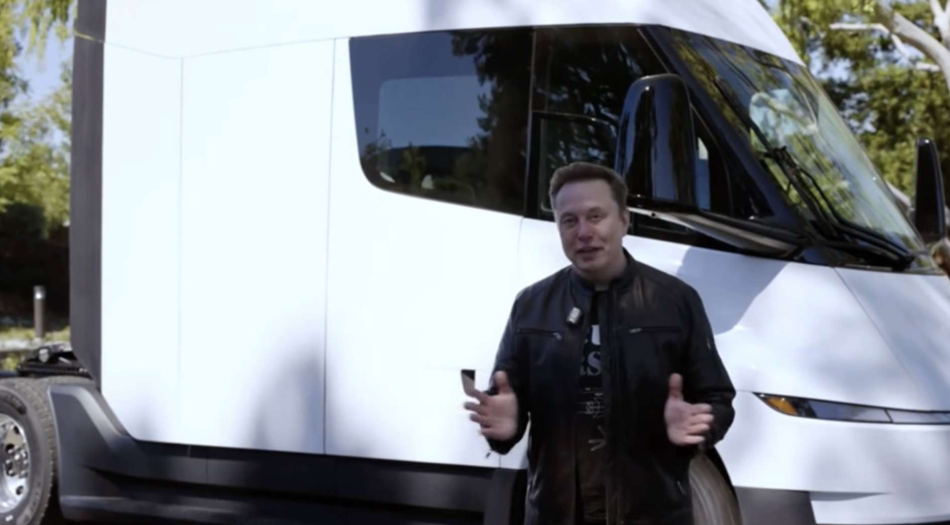 Man gesturing in front of white Tesla Semi truck outdoors