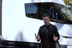 Man gesturing in front of white Tesla Semi truck outdoors