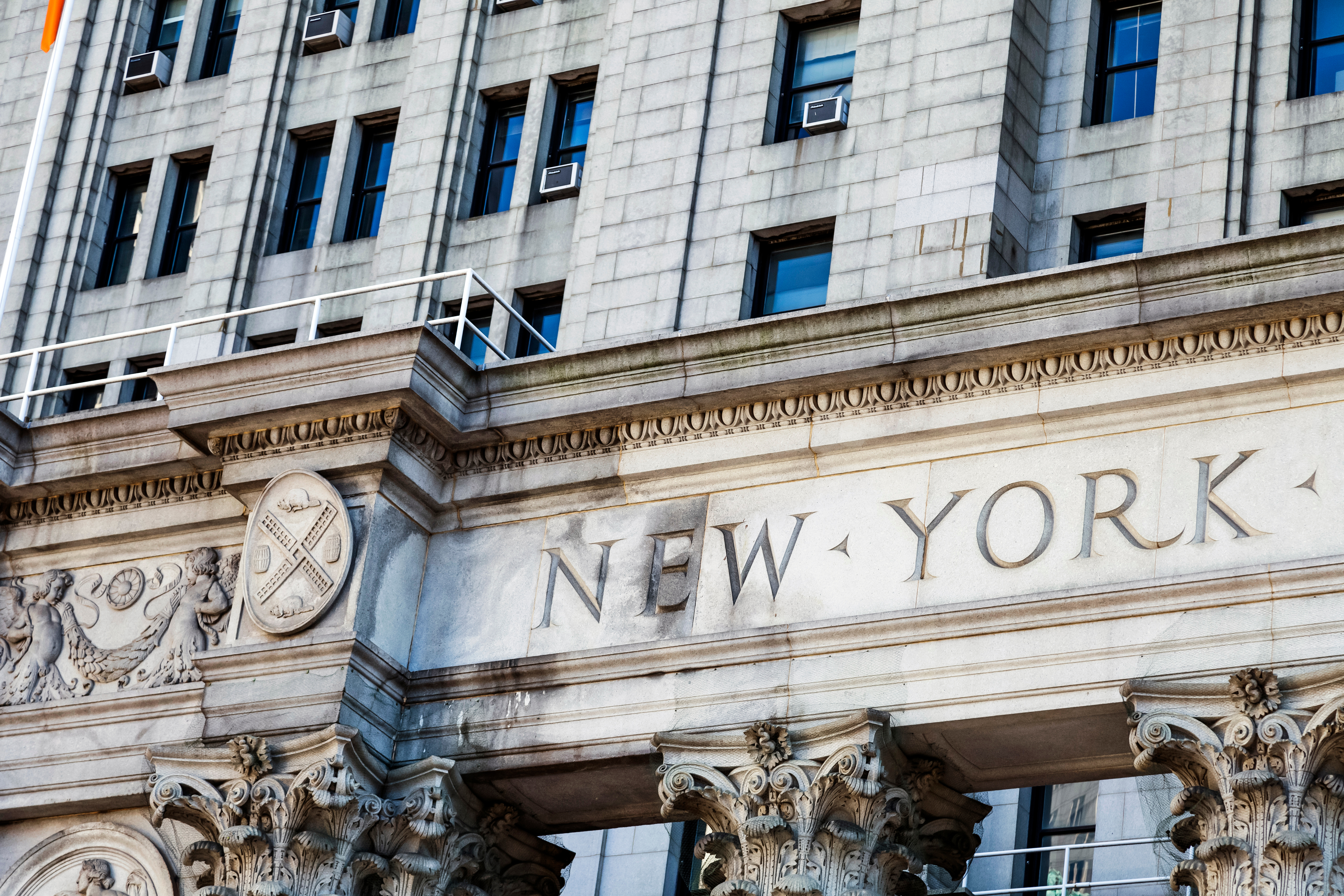 Ornate stone building facade with 'NEW YORK' carved text and classical Corinthian columns