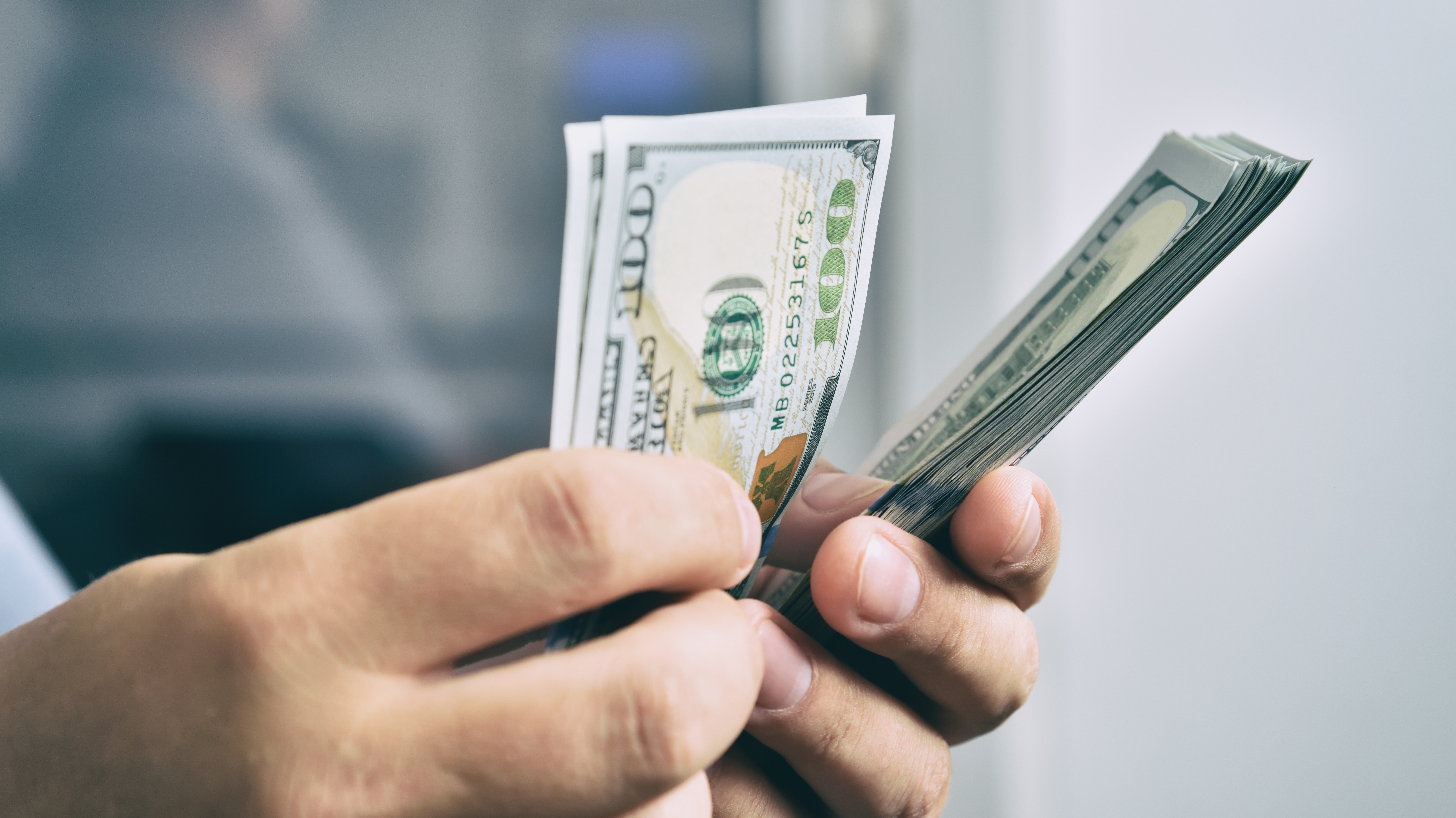 Person holding multiple U.S. dollar bills in their hand