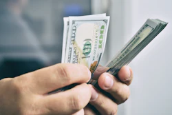Person holding multiple U.S. dollar bills in their hand