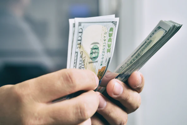 Person holding multiple U.S. dollar bills in their hand
