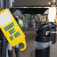 Yellow 'Sorry Out of Use' safety tag on gas pump nozzle at service station