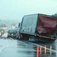 Multi-vehicle highway collision on wet freeway during rainy conditions with truck and passenger cars