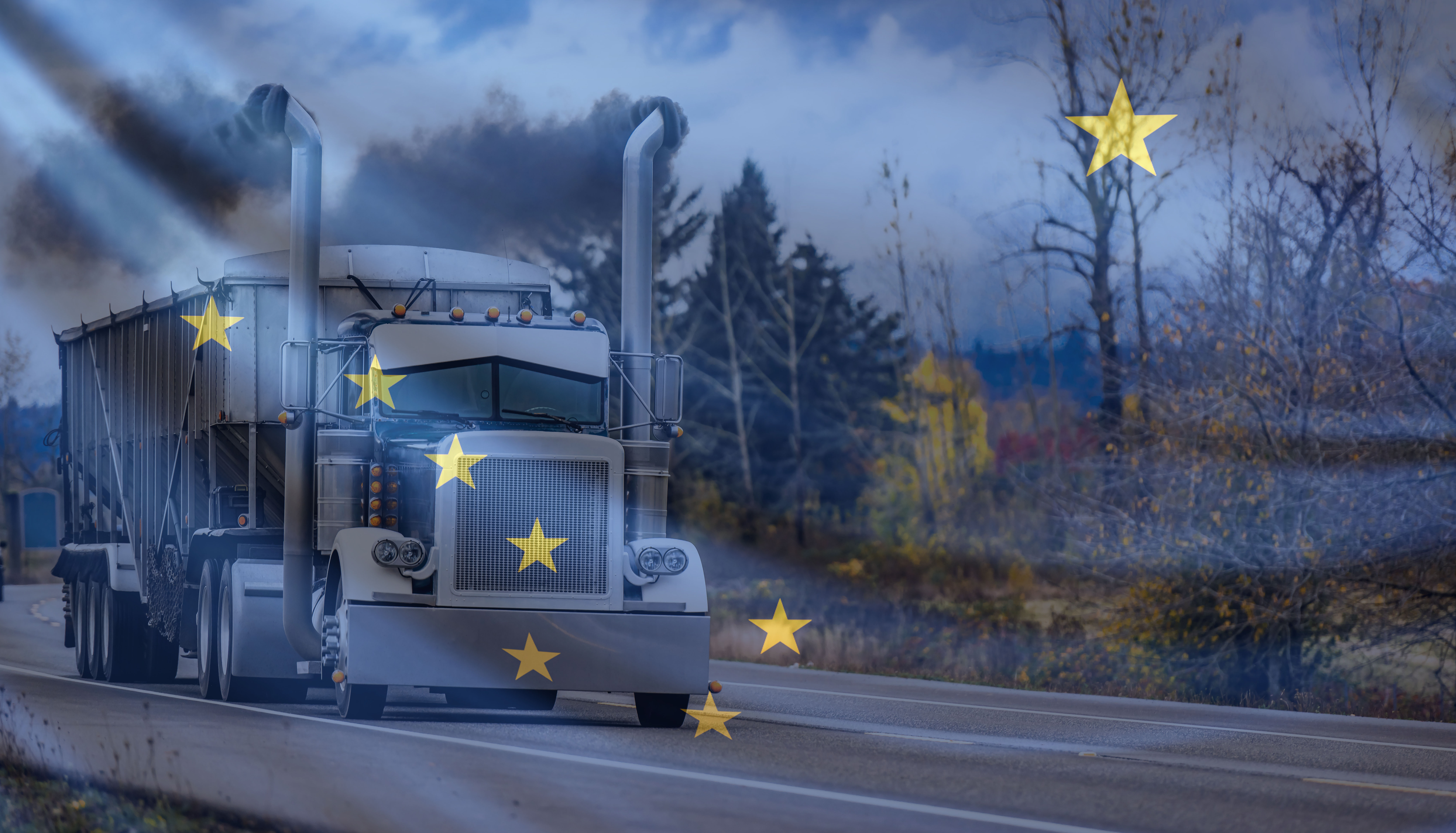 White semi-truck with yellow stars driving through a barren landscape under a cloudy blue sky