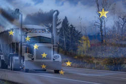 White semi-truck with yellow stars driving through a barren landscape under a cloudy blue sky