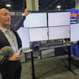 Businessman presenting software dashboard on multiple monitors at tech conference booth