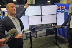 Businessman presenting software dashboard on multiple monitors at tech conference booth