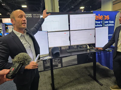Businessman presenting software dashboard on multiple monitors at tech conference booth
