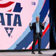 Professional speaker presenting at podium with ATA logo displayed on stage backdrop