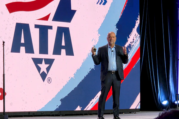 Professional speaker presenting at podium with ATA logo displayed on stage backdrop