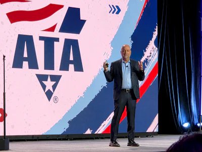 Professional speaker presenting at podium with ATA logo displayed on stage backdrop