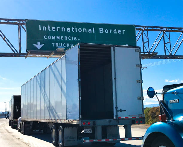 Green highway sign directing commercial trucks to International Border with downward arrow