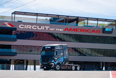 Circuit of the Americas racing venue with blue race truck parked beneath branded signage on multi-story facility