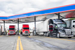 Semi-trucks parked under blue and red canopy at commercial truck stop facility