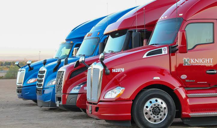 Fleet of blue and red semi-trucks lined up with Knight Transportation branding displayed on vehicles