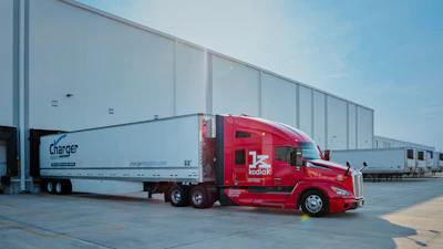 Red Kodiak semi-truck with white Charger Logistics trailer parked at industrial facility