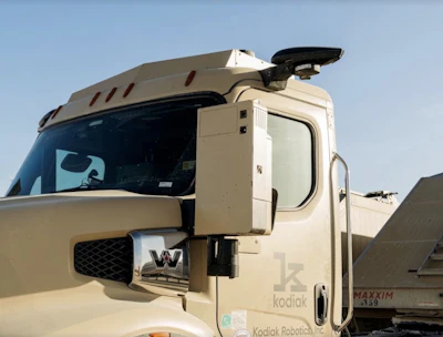 Cream-colored autonomous truck with Kodiak Robotics branding and black mirror assembly against clear sky