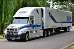 White and blue Marten Transport semi-truck with trailer on a tree-lined road