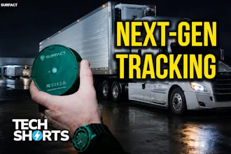 Surfact GPS tracking device held in hand with semi-truck in background at night, advertising next-generation fleet tracking technology