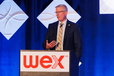 Professional man speaking at WEX corporate podium during business conference presentation