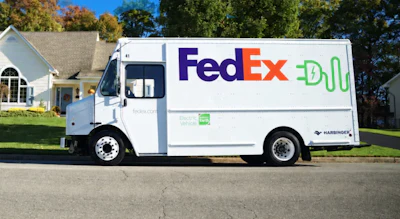 FedEx electric delivery truck parked on residential street with house in background