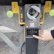 Person's hand using yellow and gray parking meter payment kiosk with digital screen
