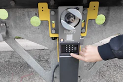 Person's hand using yellow and gray parking meter payment kiosk with digital screen