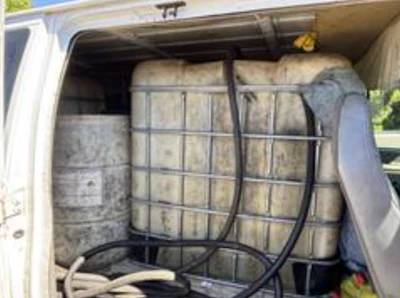 Van cargo bed filled with hay bales secured by black netting straps