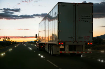 Semi-truck with refrigerated trailer driving on highway at sunset with dramatic cloudy sky
