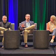 Three professionals participate in a panel discussion on stage with blue and green lighting backdrop