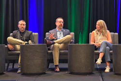 Three professionals participate in a panel discussion on stage with blue and green lighting backdrop