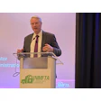 Professional speaker at podium with NMFTA Cybersecurity Conference logo during presentation event