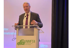 Professional speaker at podium with NMFTA Cybersecurity Conference logo during presentation event