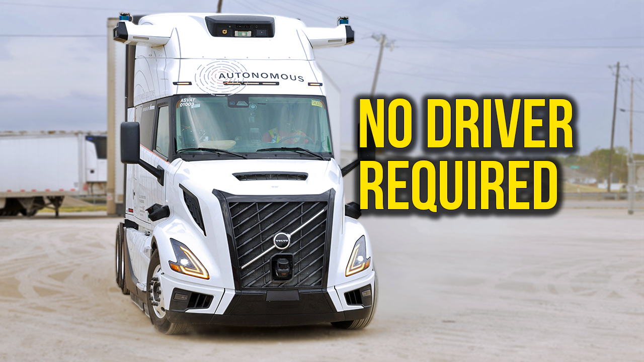 White autonomous semi-truck with 'No Driver Required' text overlay in parking lot