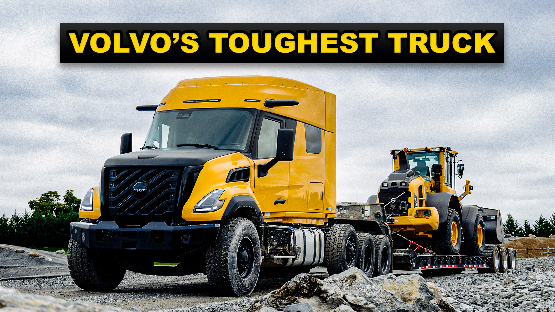 Yellow Volvo semi-truck with construction equipment on gravel site