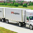 XPO Logistics semi-truck with double trailers driving on highway through suburban landscape