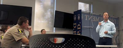 Professional presenting at podium during indoor meeting with attendees seated nearby